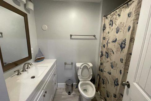 a bathroom with a toilet, sink, and shower.