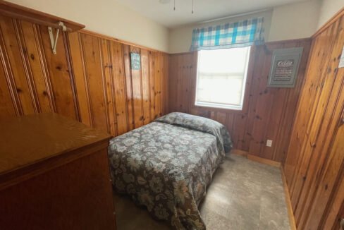 a bedroom with wood paneling and a bed.