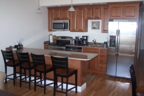 a kitchen with a refrigerator, stove, microwave, and dining table.