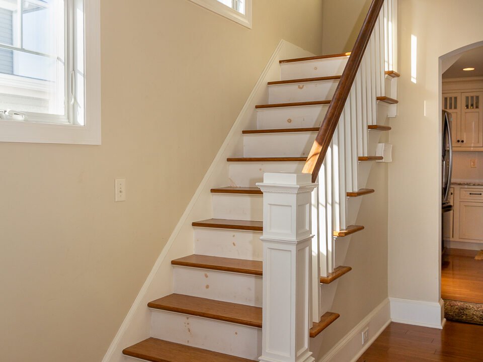 a white staircase with wooden steps in a house.