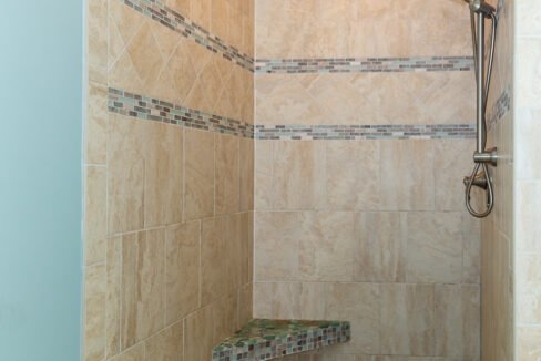 a walk in shower sitting next to a tiled wall.