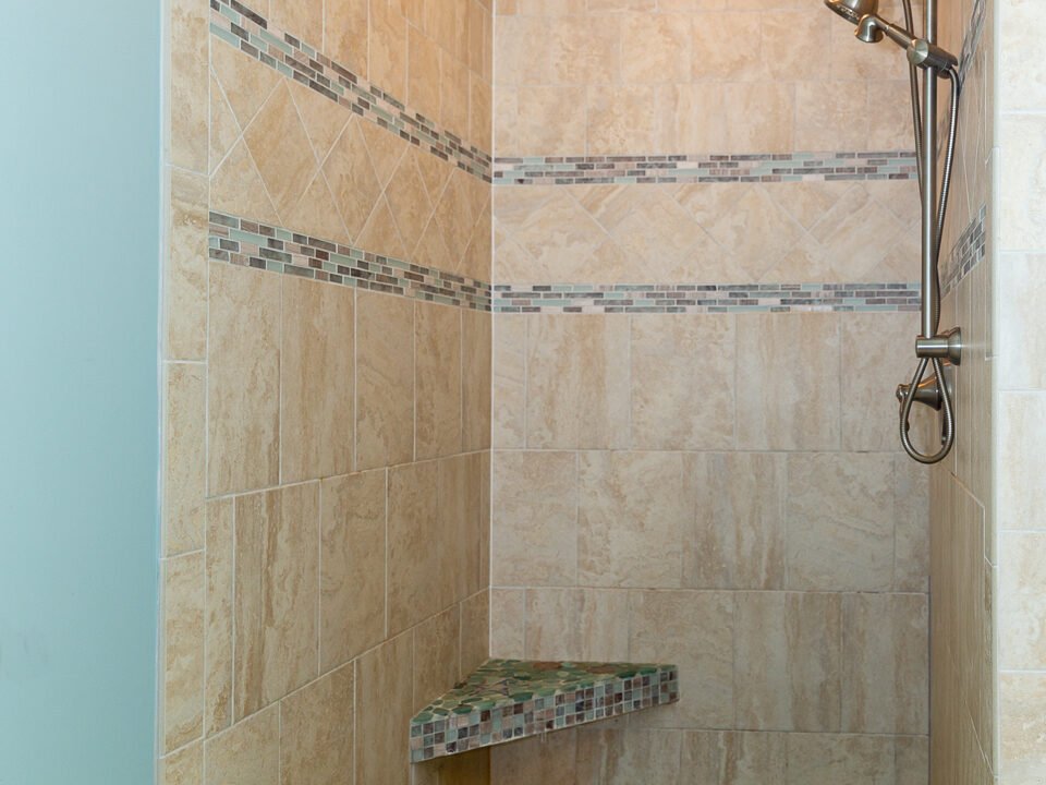 a walk in shower sitting next to a tiled wall.