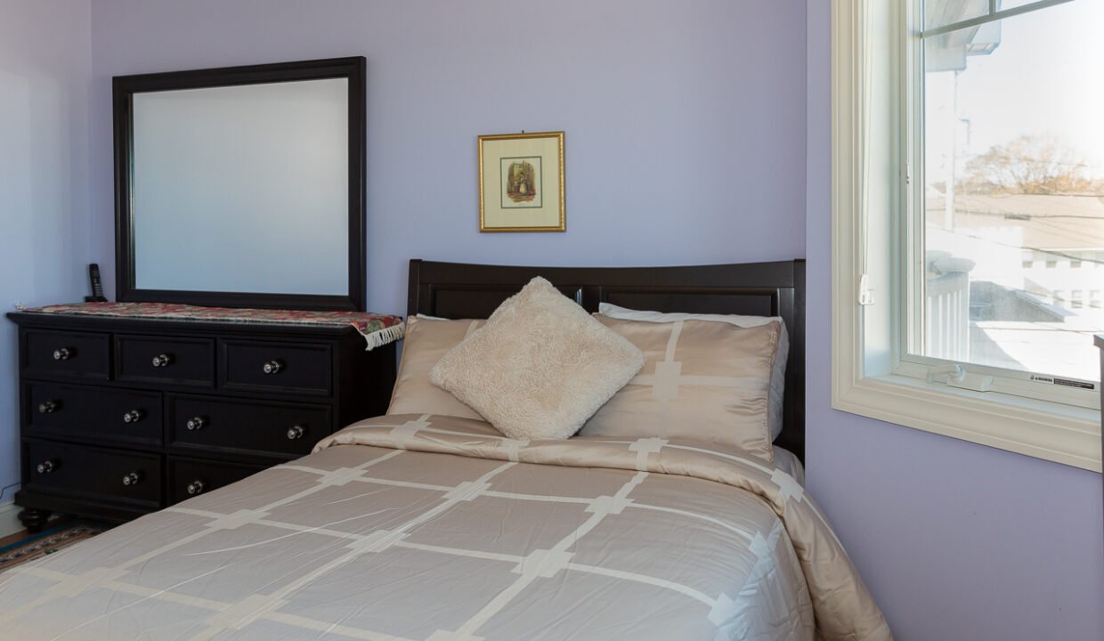 a bedroom with a bed, dresser and mirror.