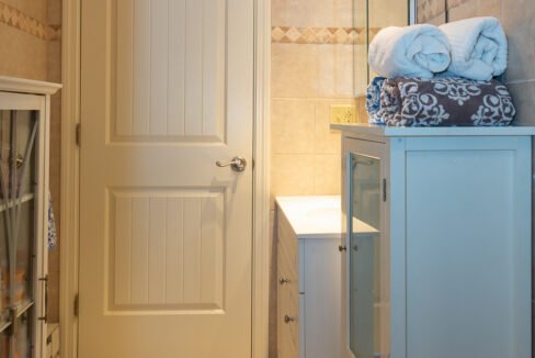 a bathroom with a white door and a white cabinet.