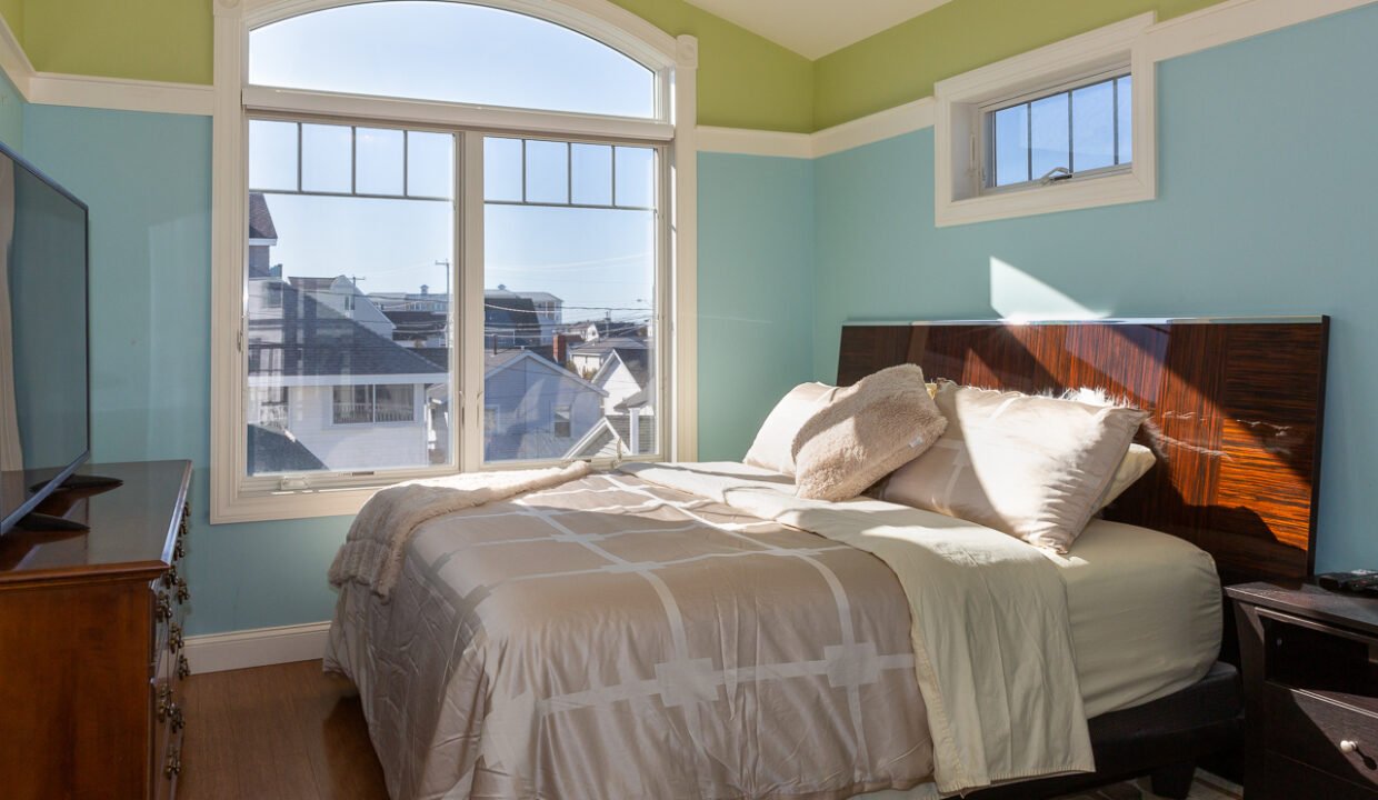 a bedroom with a bed and a large window.