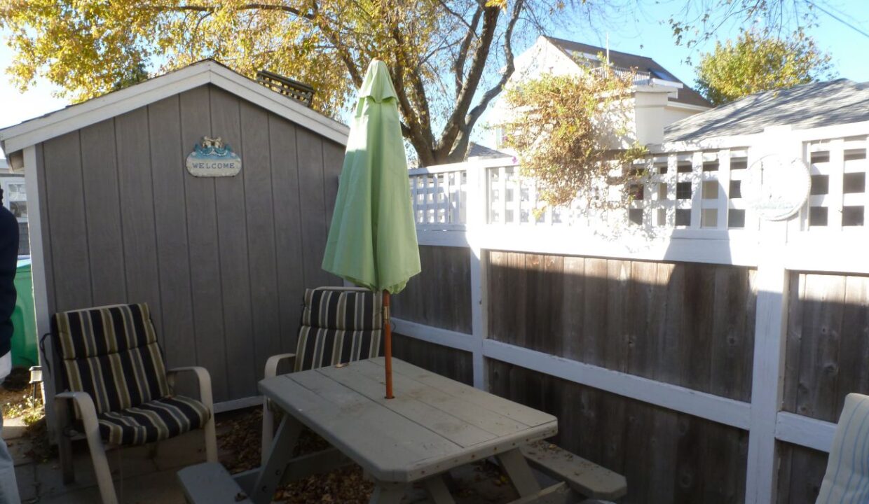 a wooden picnic table sitting next to a white fence.