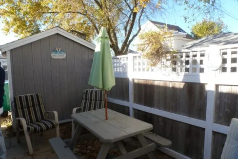 a wooden picnic table sitting next to a white fence.