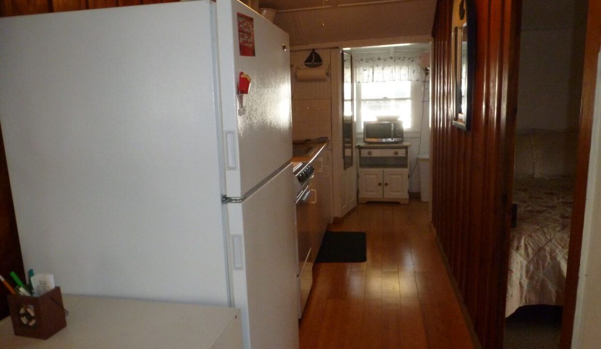 a kitchen with a refrigerator, stove, microwave and a bed.