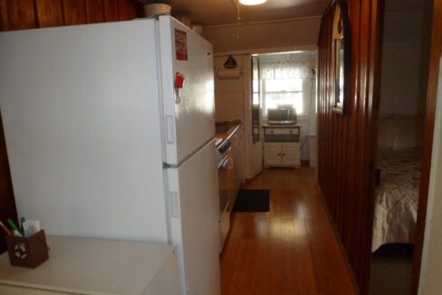 a kitchen with a refrigerator, stove, microwave and a bed.