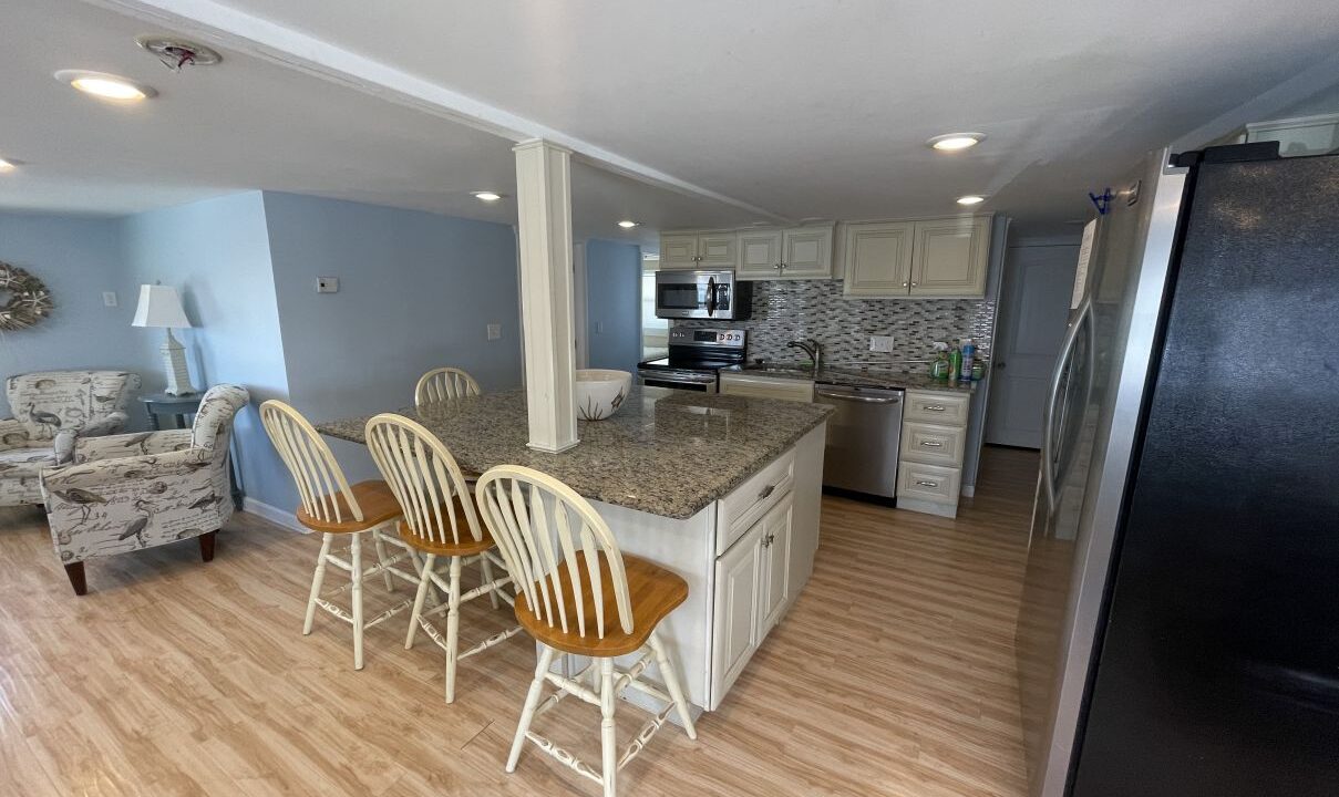 a kitchen and living room with a refrigerator.