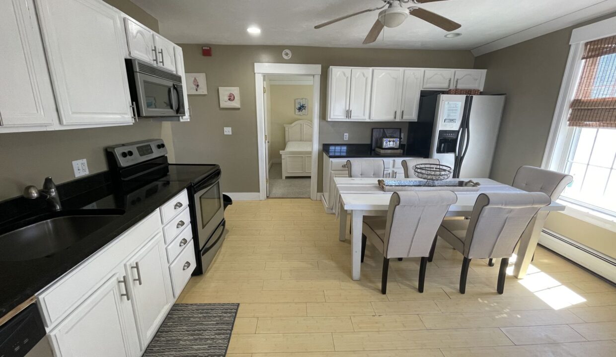 a kitchen with white cabinets and black counter tops.