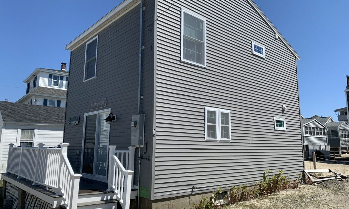 a gray house with a white staircase leading up to it.