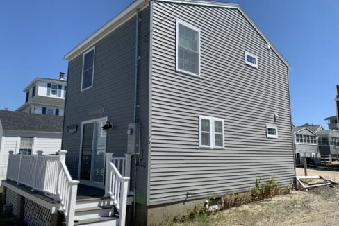 a gray house with a white staircase leading up to it.