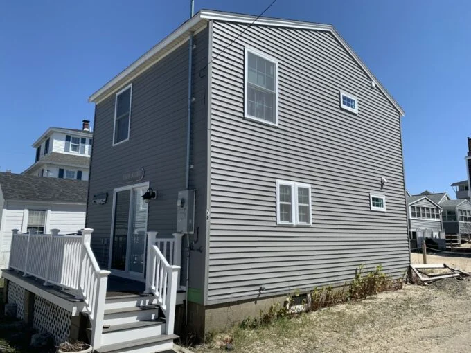 a gray house with a white staircase leading up to it.