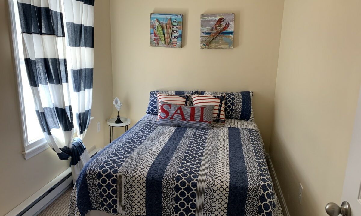 a bedroom with a blue and white bedspread and two paintings on the wall.