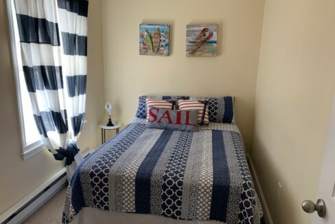 a bedroom with a blue and white bedspread and two paintings on the wall.