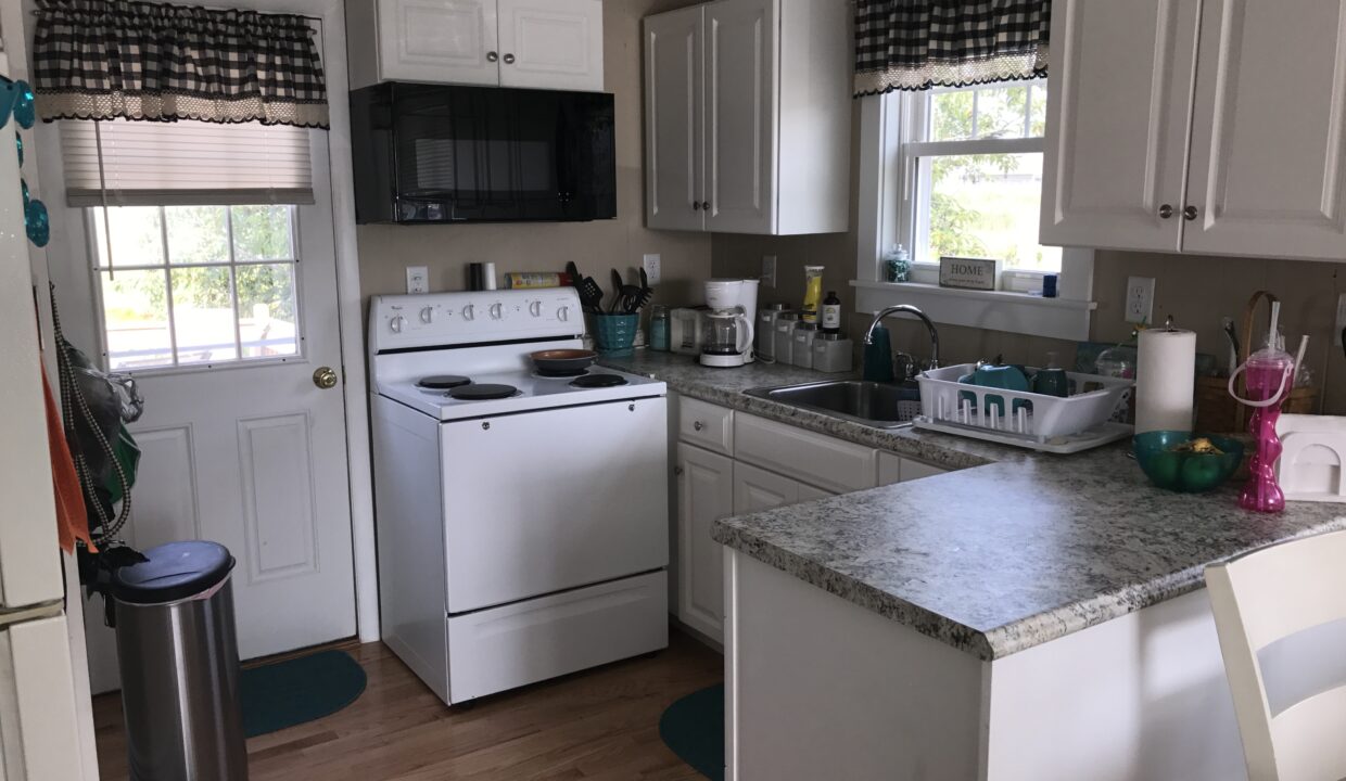 a kitchen with a stove, dishwasher, sink and a trash can.