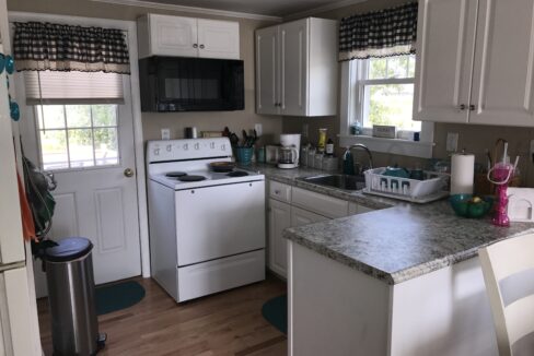 a kitchen with a stove, dishwasher, sink and a trash can.