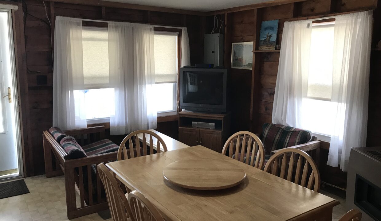 a dining room table with chairs and a television.