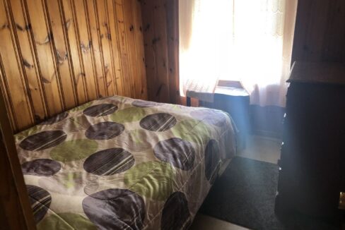 a bedroom with wood paneling and a bed.