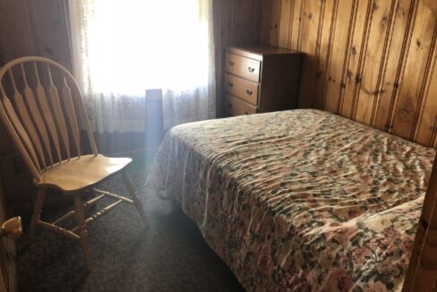 a bedroom with a bed, dresser and chair.