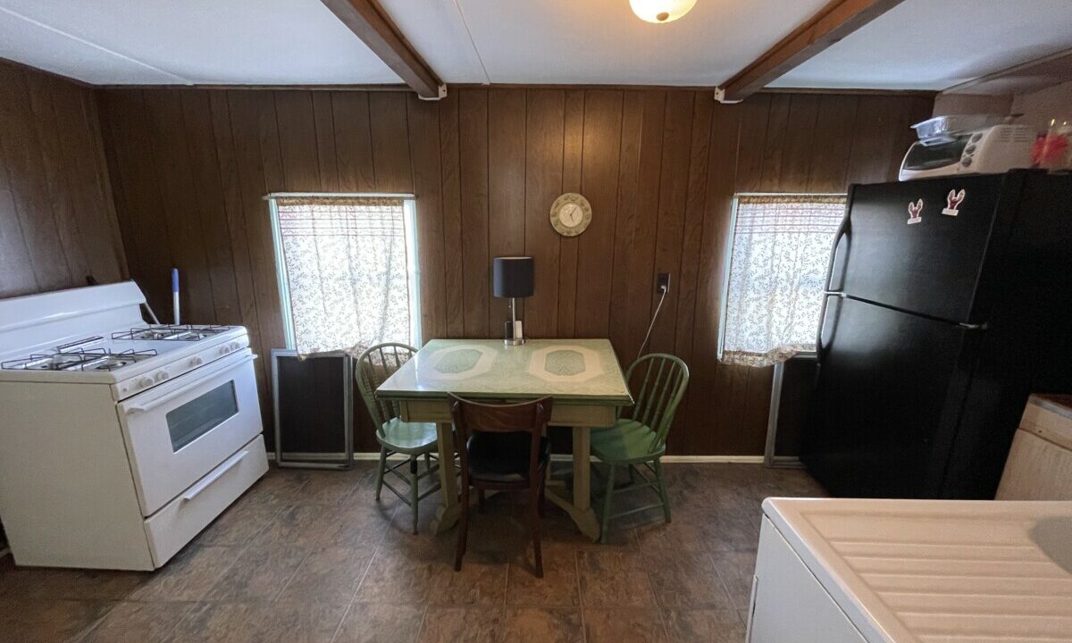 a kitchen with a table, stove and refrigerator.