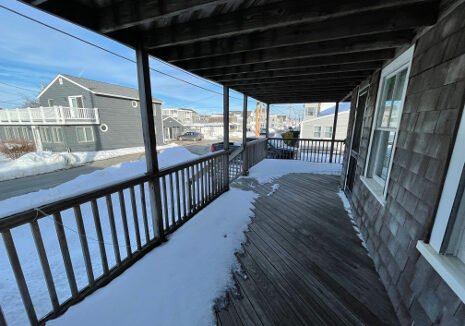 a porch covered in snow next to a building.