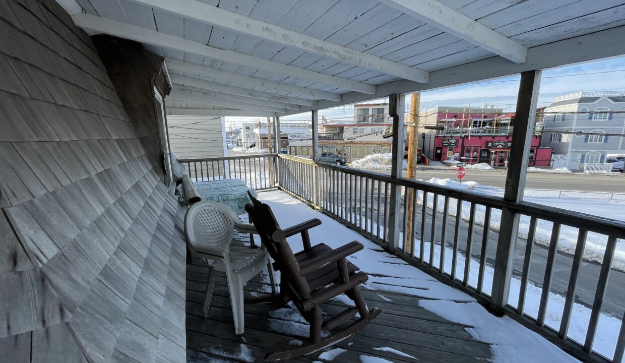 a rocking chair on a porch covered in snow.