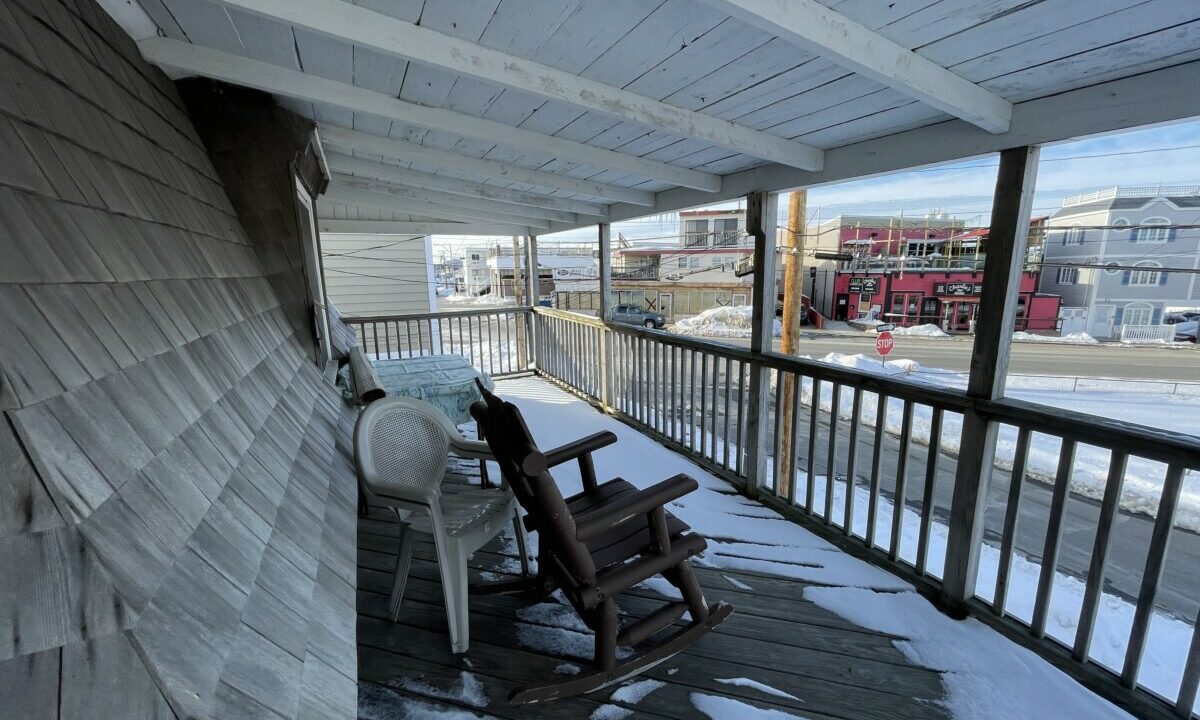 a rocking chair on a porch covered in snow.