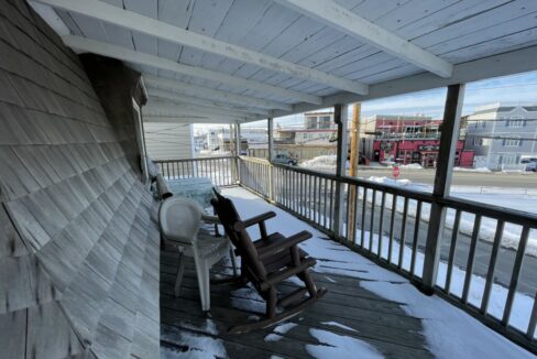 a rocking chair on a porch covered in snow.