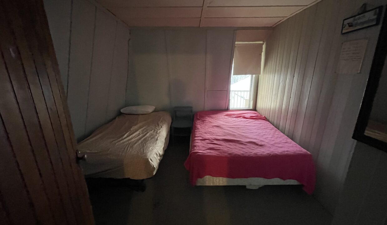 a small room with two beds and a window.