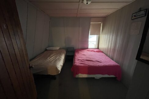 a small room with two beds and a window.