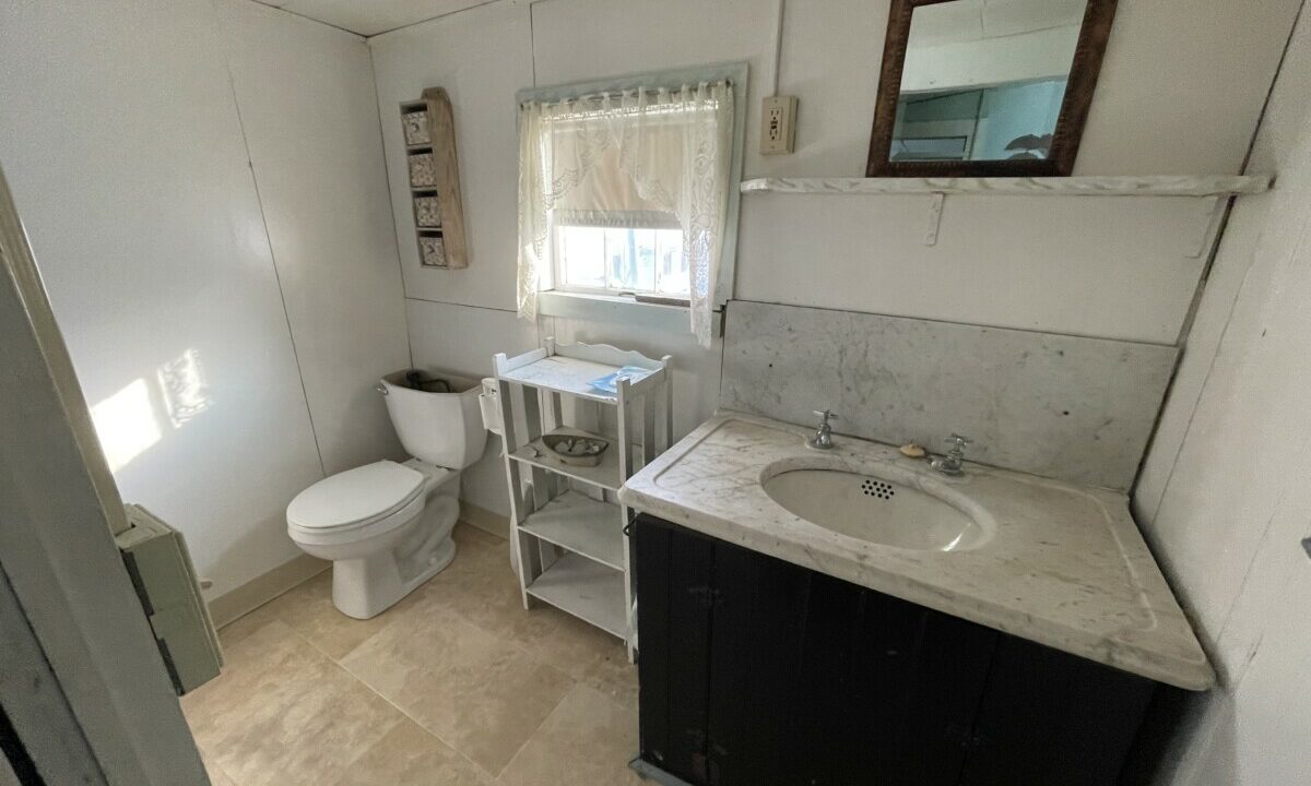 a bathroom with a toilet, sink, and mirror.