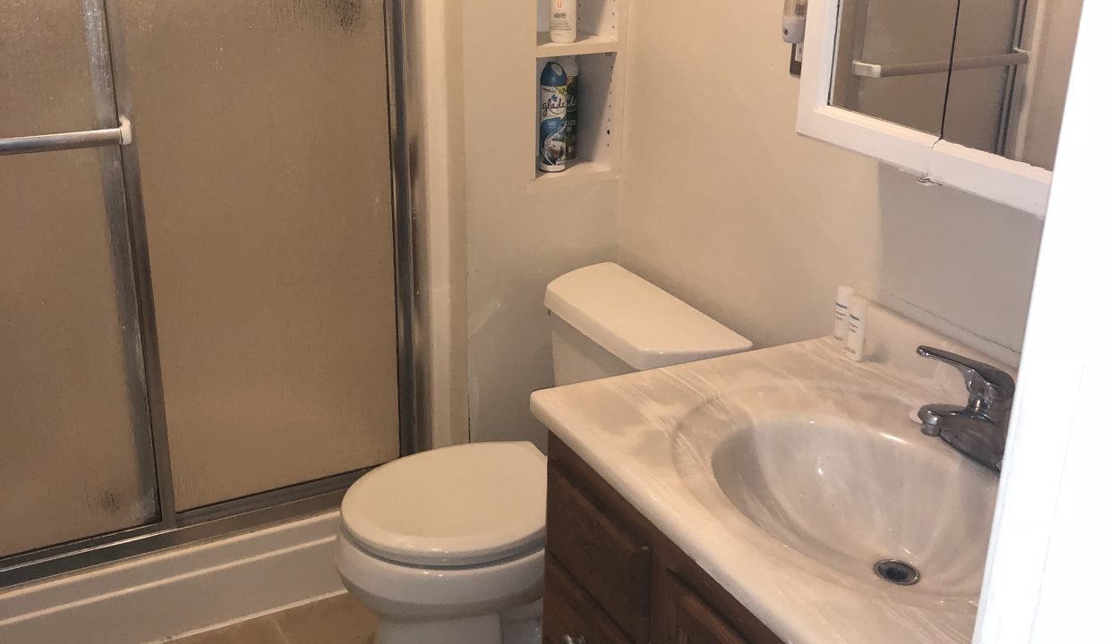 a bathroom with a toilet, sink, and shower.