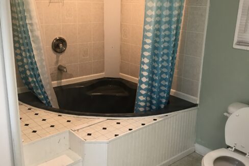 a bath room with a toilet a sink and a bath tub.