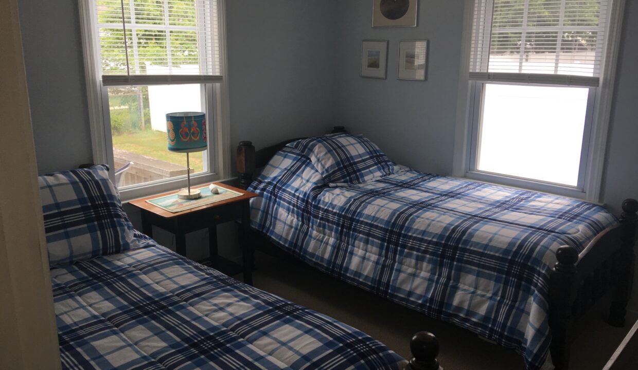 a bedroom with two beds and two windows.