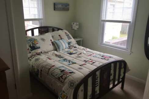 a bed sitting in a bedroom next to two windows.