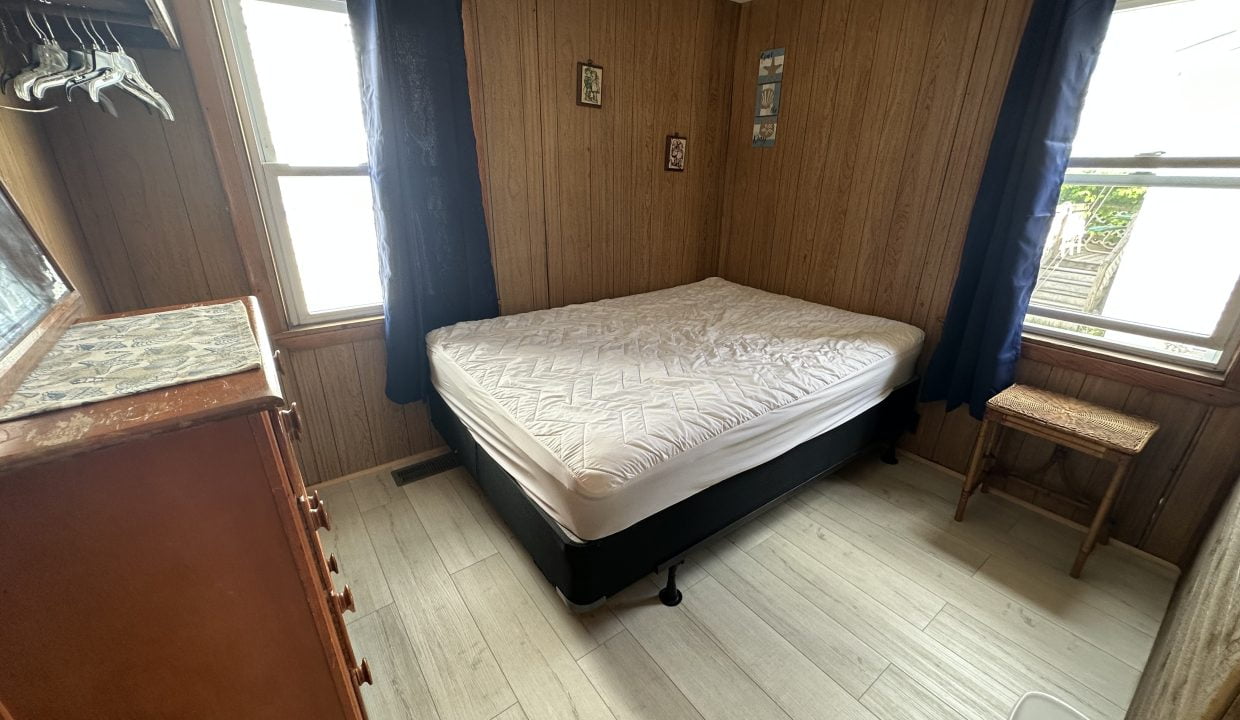 a small bedroom with a bed and two windows.