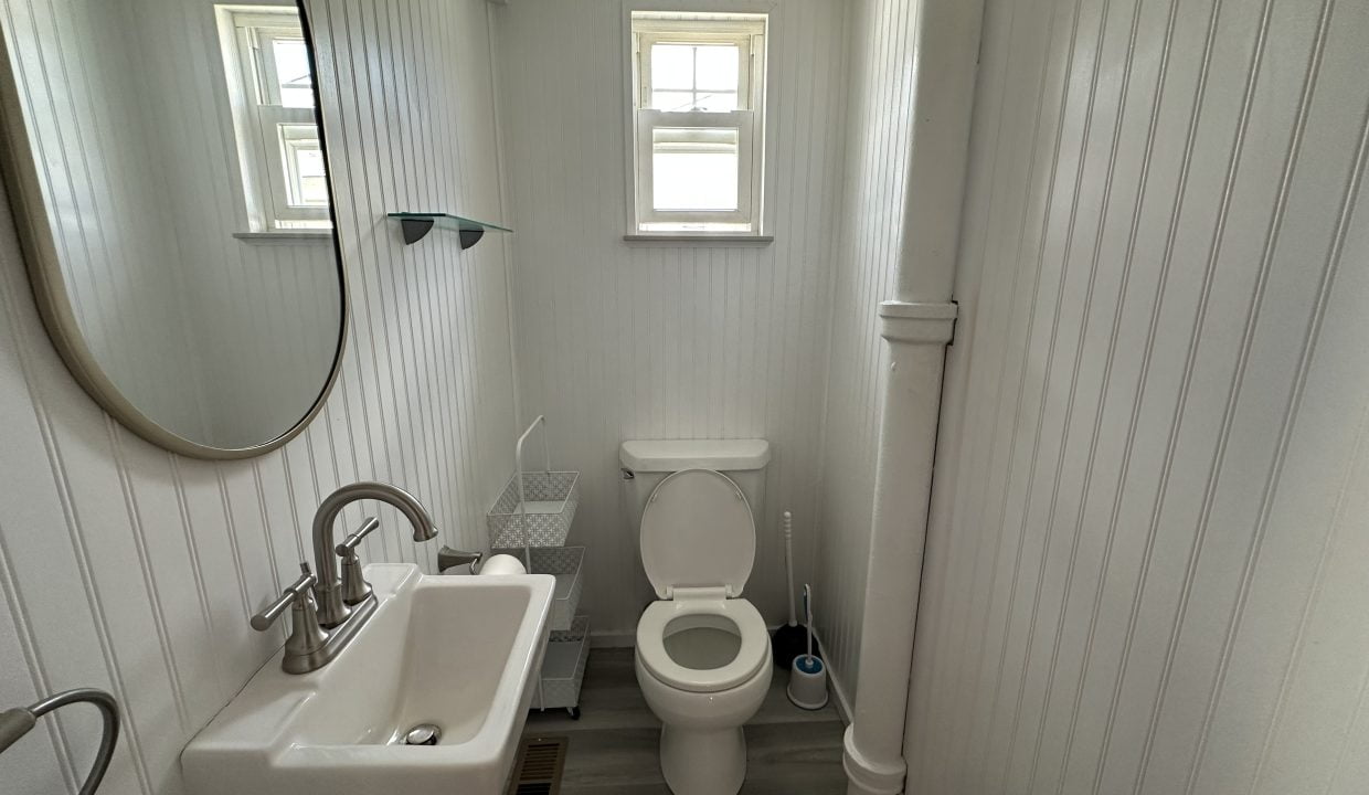 a bathroom with a toilet, sink and mirror.