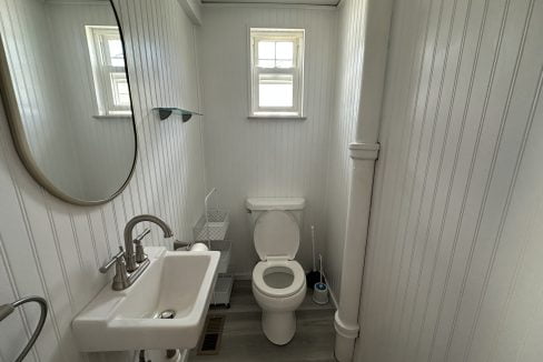 a bathroom with a toilet, sink and mirror.