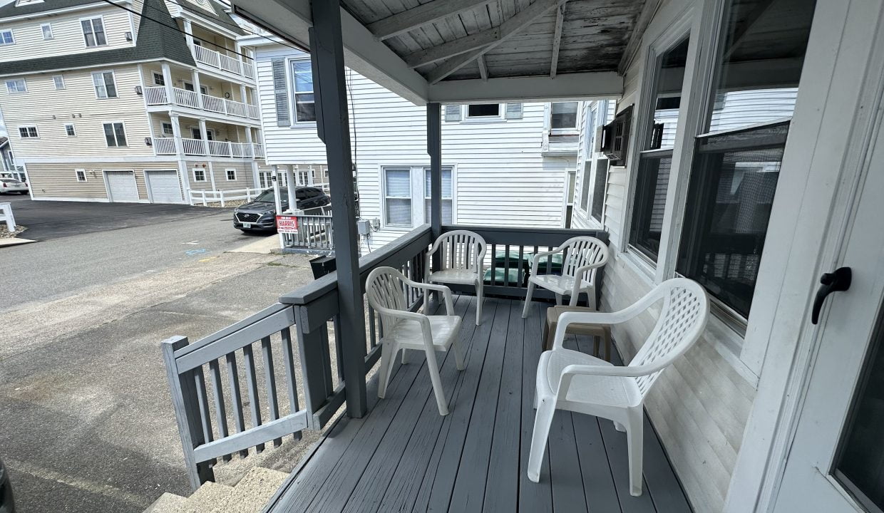 a porch with two chairs and a table on it.