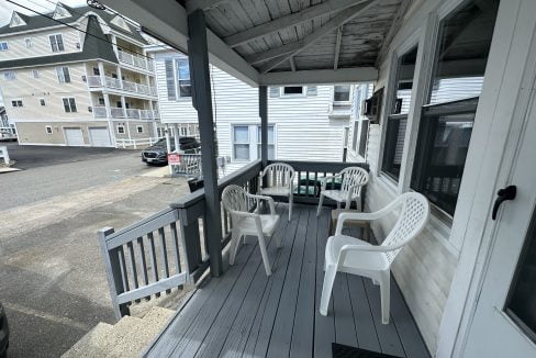 a porch with two chairs and a table on it.