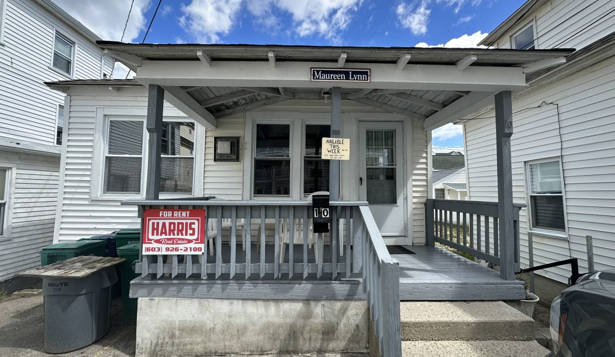 a small white house with a sign on the front porch.