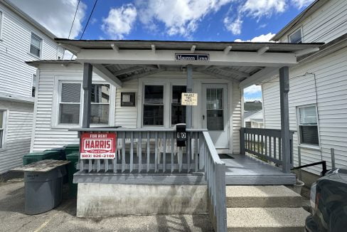 a small white house with a sign on the front porch.