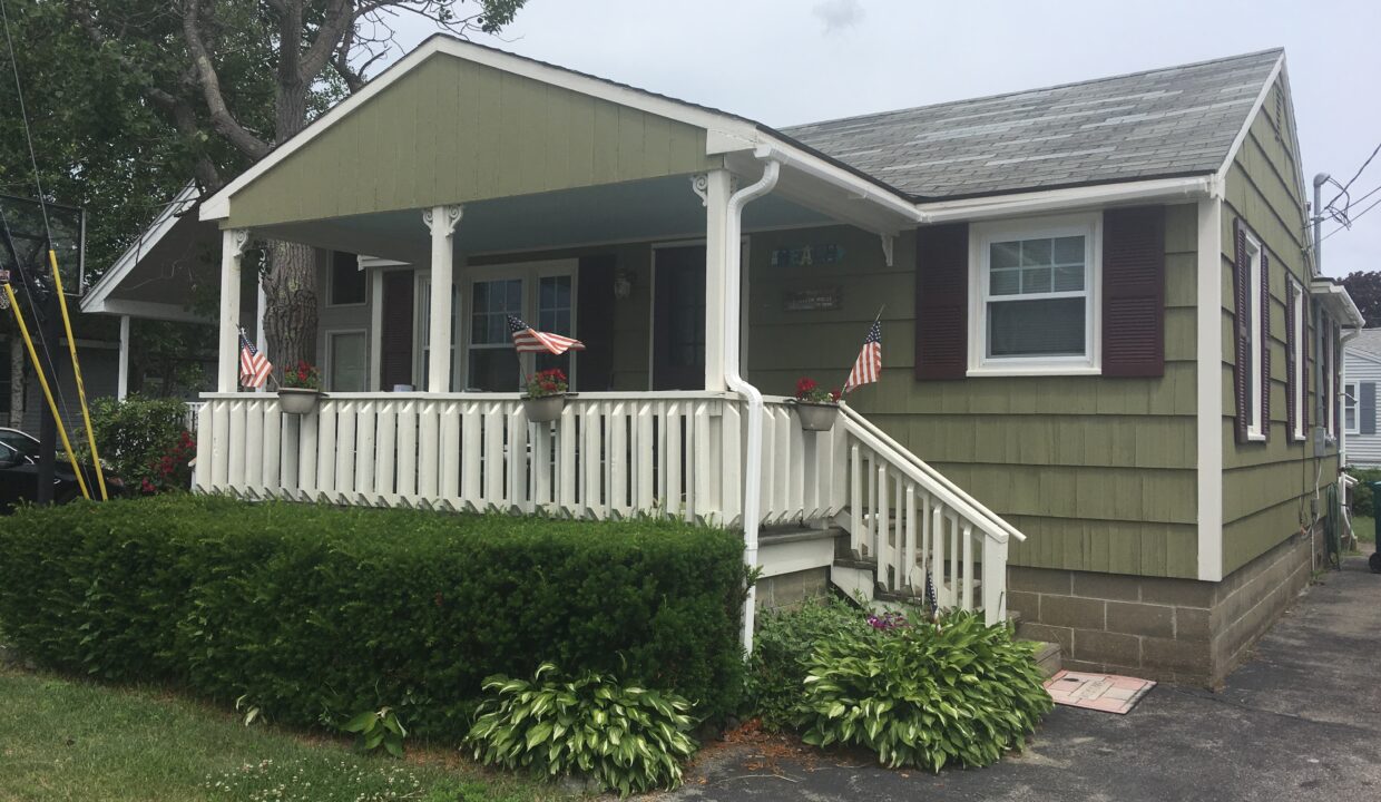 a house with a white porch and red shutters.