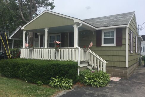 a house with a white porch and red shutters.