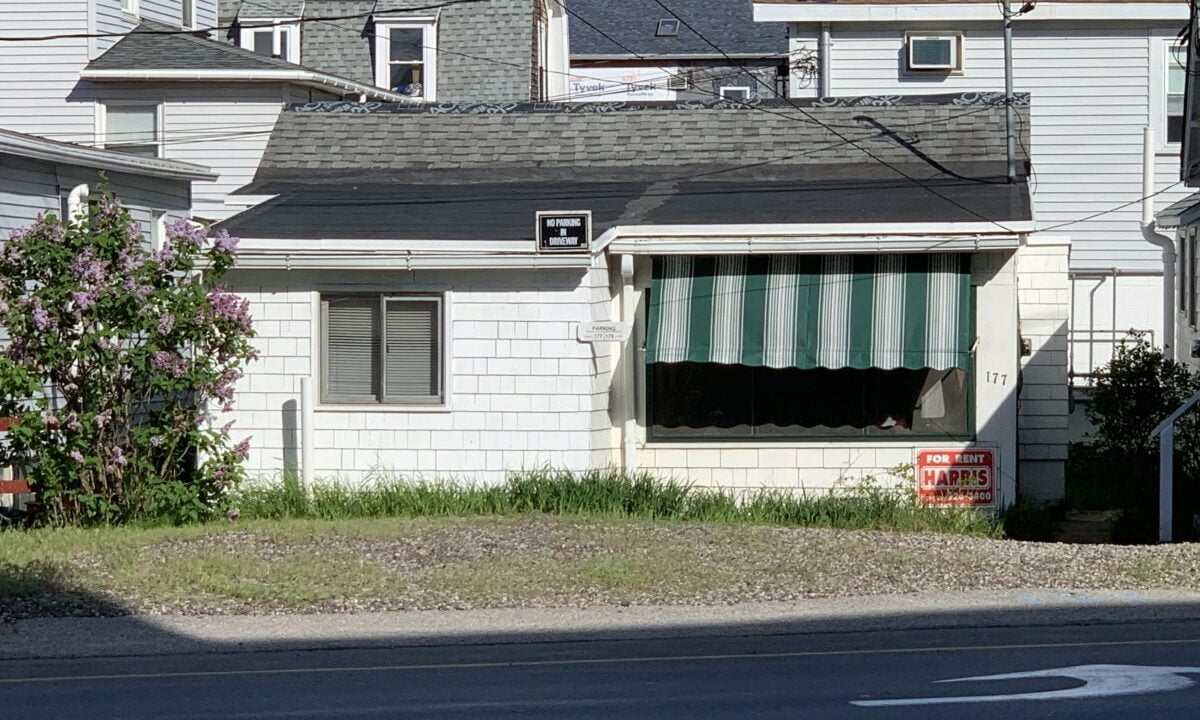 a white house with a green and white striped awning.