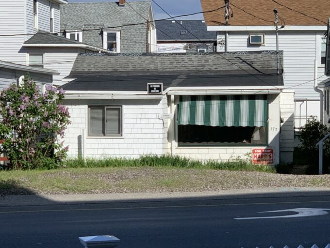 a white house with a green and white striped awning.