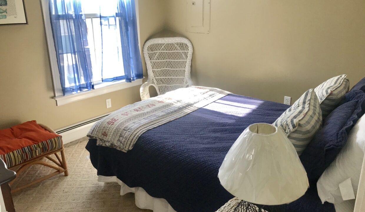 a bedroom with a bed, chair and window.