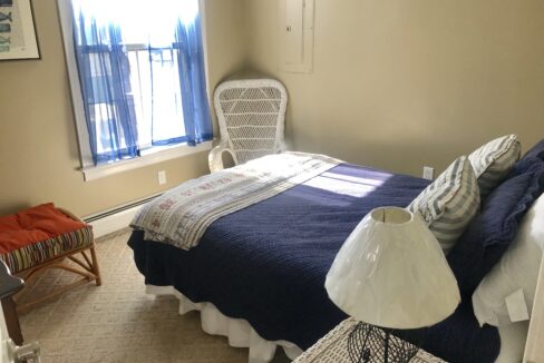 a bedroom with a bed, chair and window.